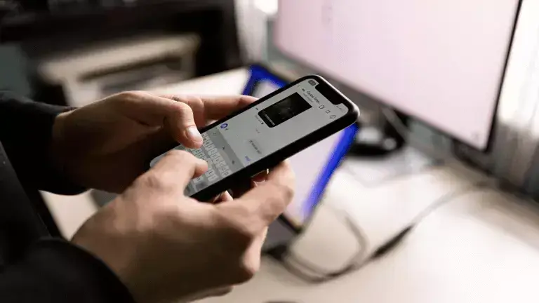 Social Media Growth article link and header image - Person holding a mobile phone with computer screen in background
